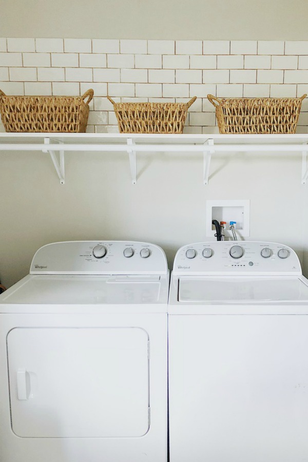 White subway tile above washer and dryer.