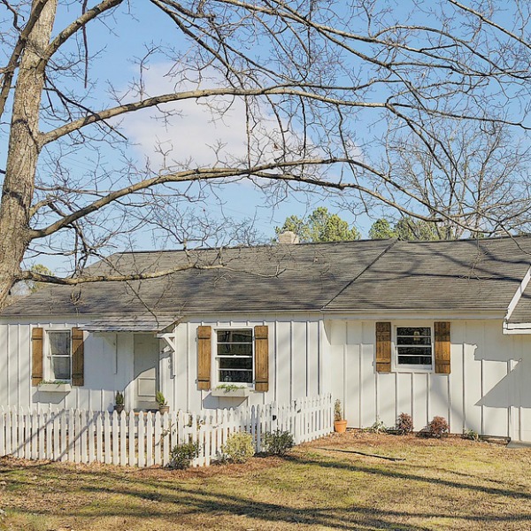 Charming white cottage exterior with board and batten and rustic shutters.