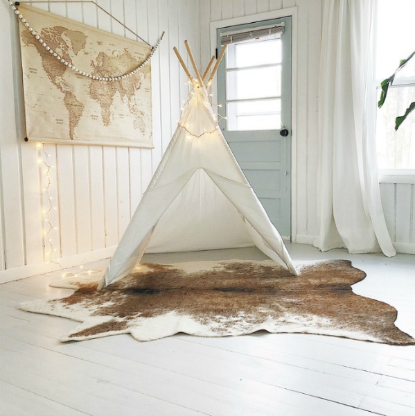 White teepee and cowhide rug in modern farmhouse kids space with paneled walls.