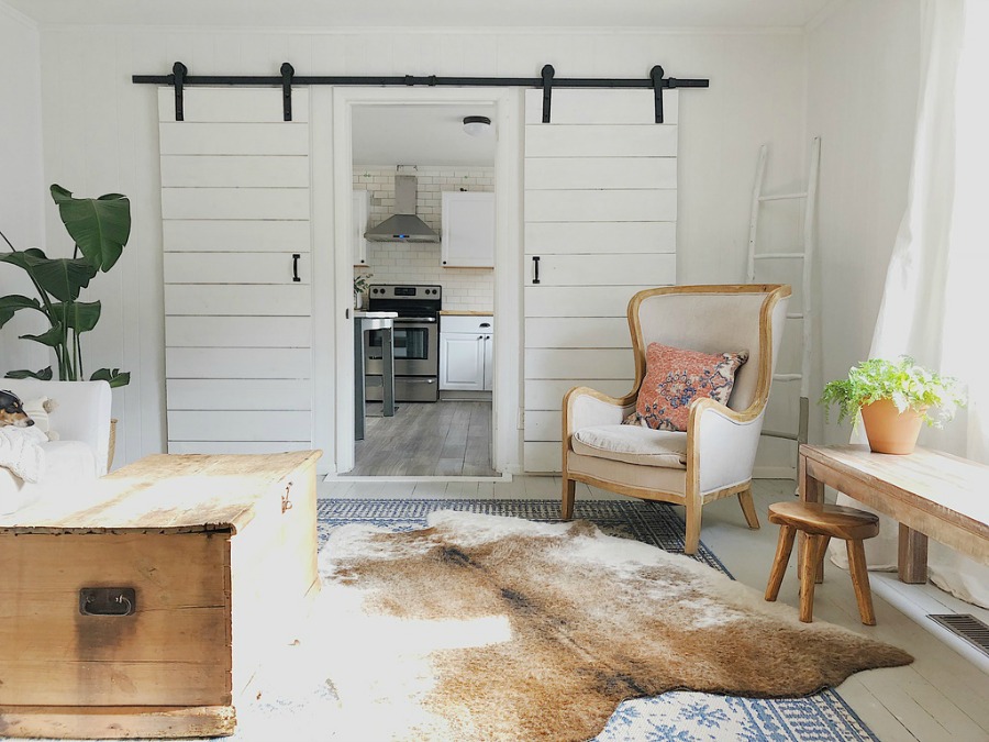 White barn doors in modern farmhouse space with wing chair.