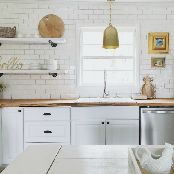 Charming white modern farmhouse kitchen with subway tile and open shelving.