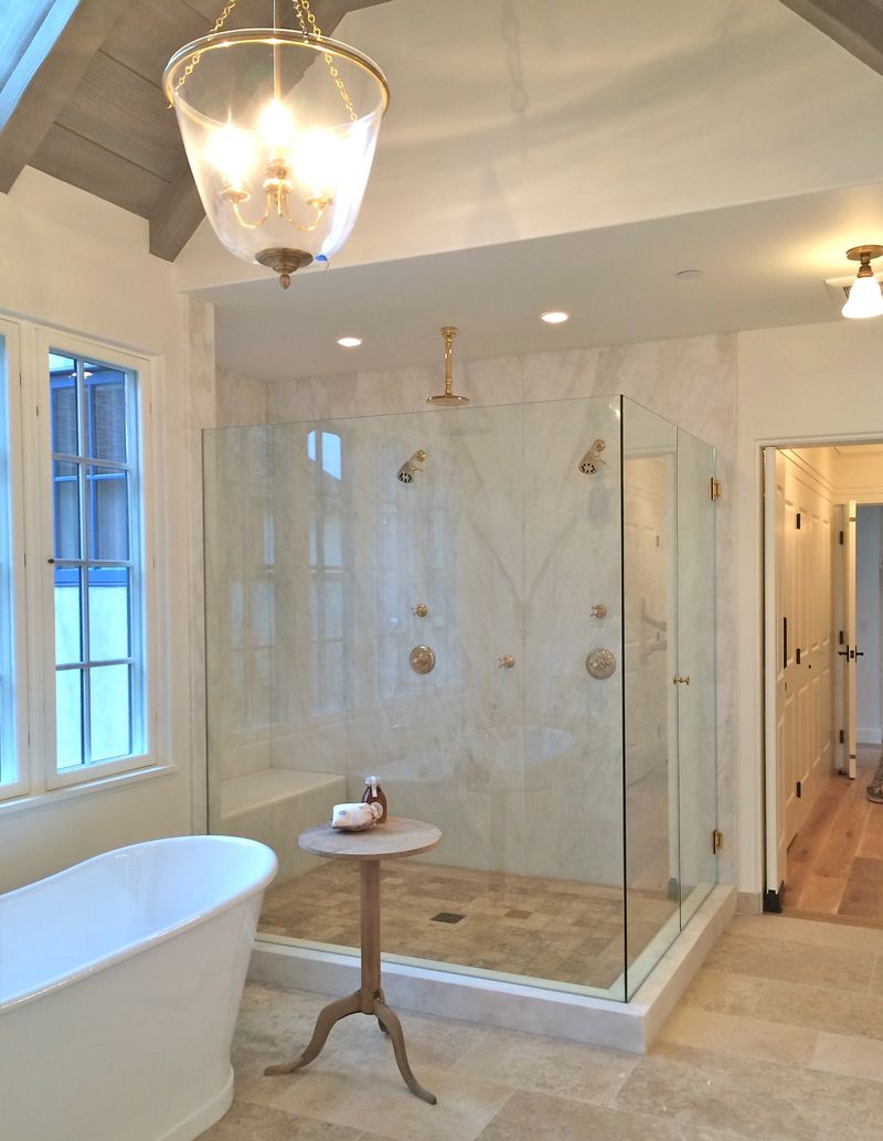 Beautiful bathroom with stone flooring and glass shower walls - Giannetti Home.