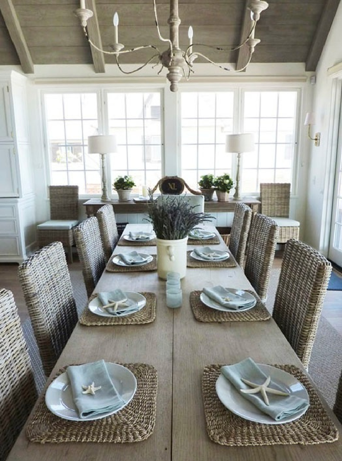 Rattan dining chairs at farmhouse table in a kitchen by Giannetti Home. See more rustic elegant French farmhouse design ideas and decor inspiration. #frenchfarmhouse #interiordesign #frenchcountry