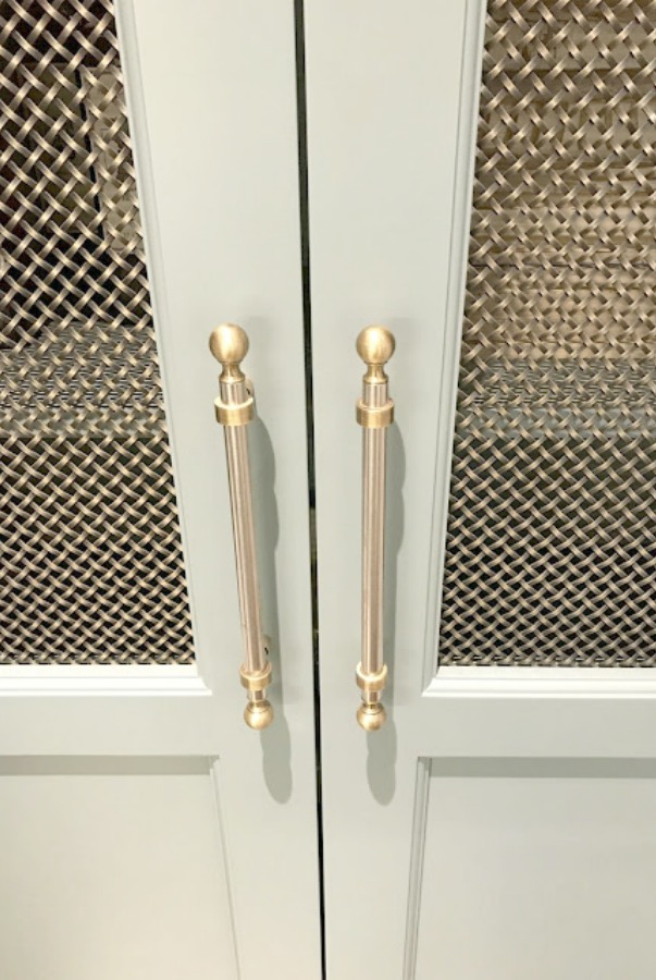 Detail of brass hardware on light blue kitchen cabinet.