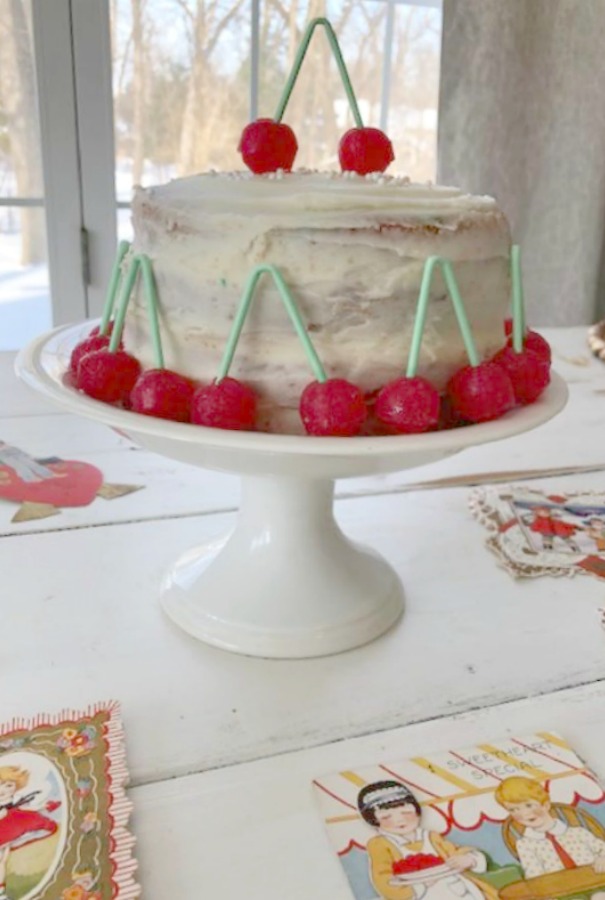 Vintage Valentine Decorations & Layer Cake. Come find simple inspiration for EASY, old fashioned, heart and love themed ideas like this simple layer cake with cherry lollipops and vintage cards on Hello Lovely Studio. #valentinesday #decorations #tablescape #layercake #vintagevalentinecards