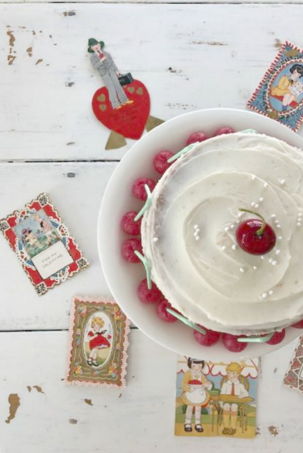 Vintage Valentine Decorations & Layer Cake. Come find simple inspiration for EASY, old fashioned, heart and love themed ideas like this simple layer cake with cherry lollipops and vintage cards on Hello Lovely Studio. #valentinesday #decorations #tablescape #layercake #vintagevalentinecards