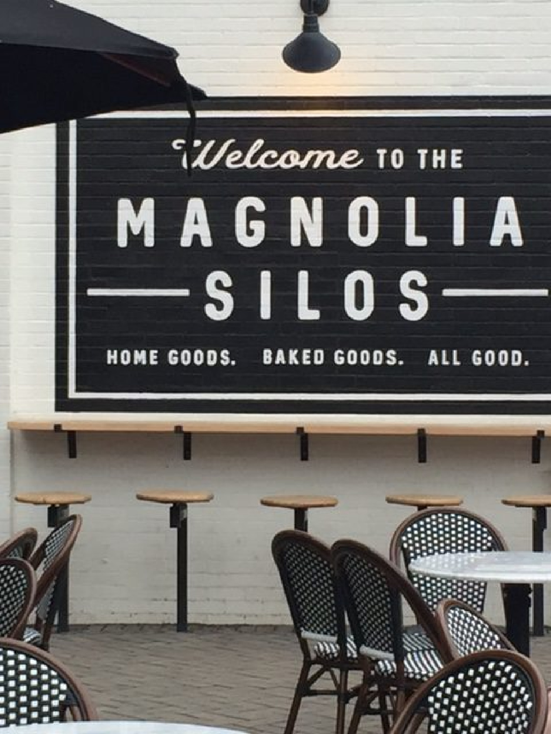 Magnolia Market Silos white brick wall of Silos Baking Co. with bar stools, Parisian bistro chairs, and black and white decor. #magnolia #silos #bakery #fixerupper