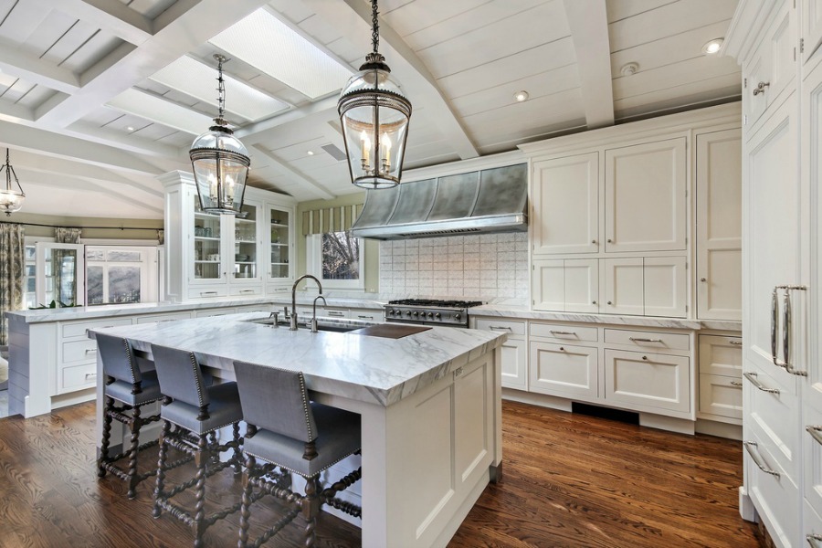 Luxurious classic white coastal kitchen with marble countertops and Shaker cabinetry.