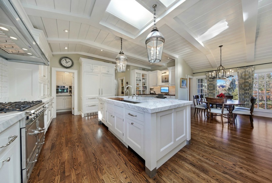 Classic and coastal style in a luxurious kitchen with dark hardwood floors and white cabinets.