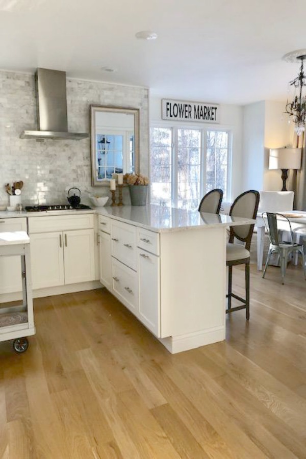 My classic white kitchen with industrial steel cart, marble backsplash, and Shaker cabinets. Hello Lovely Studio.