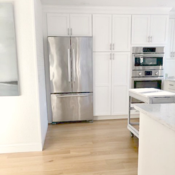 My classic white kitchen with industrial steel cart, marble backsplash, and Shaker cabinets. Hello Lovely Studio.