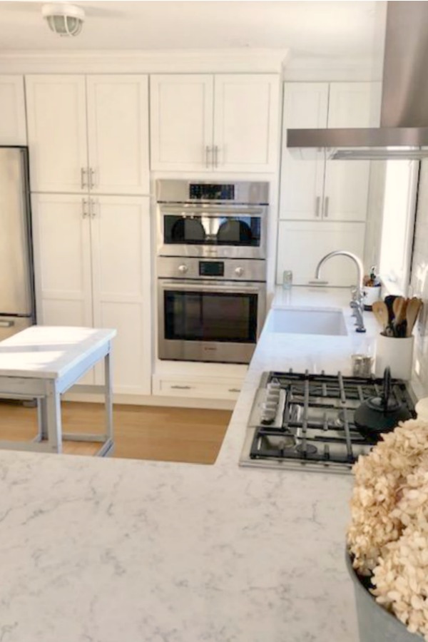 My classic white kitchen with industrial steel cart, marble backsplash, and Shaker cabinets. Hello Lovely Studio.