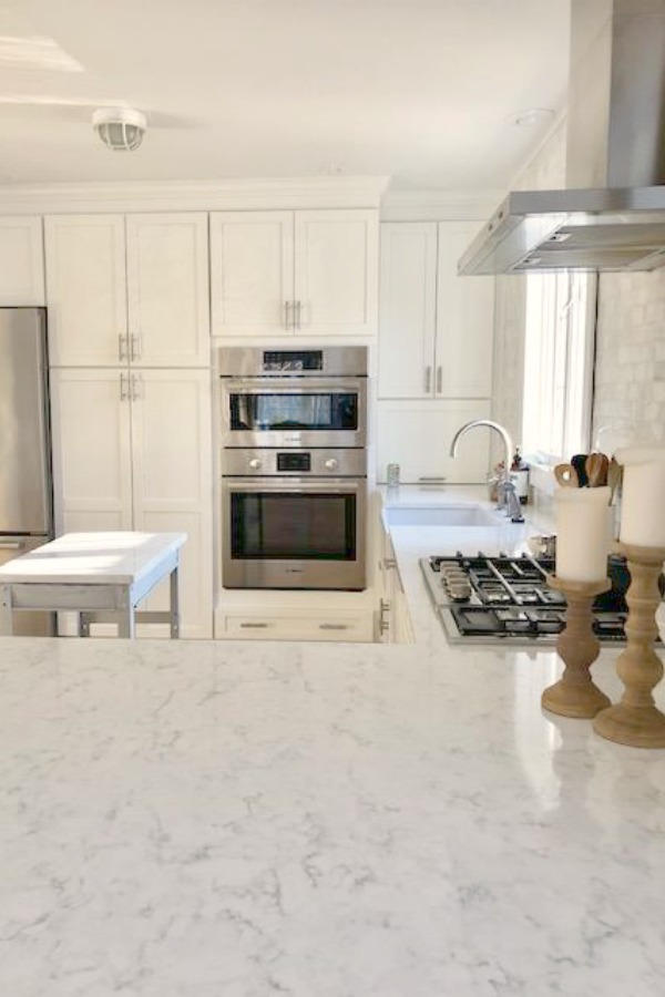 My classic white kitchen with industrial steel cart, marble backsplash, and Shaker cabinets. Hello Lovely Studio.