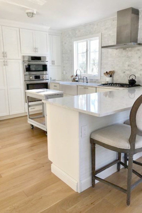 My classic white kitchen with industrial steel cart, marble backsplash, and Shaker cabinets. Hello Lovely Studio.