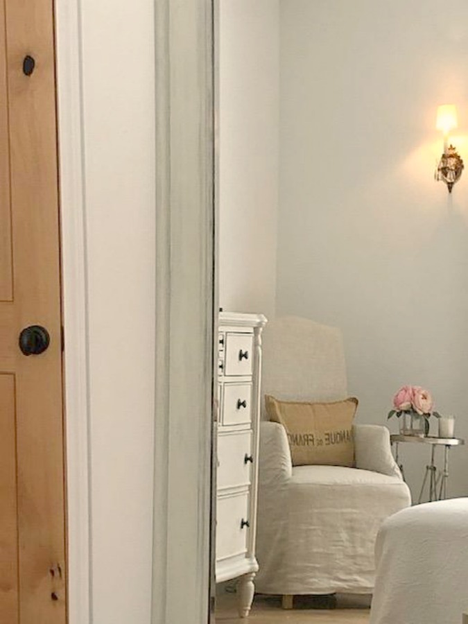 Romantic cottage bedroom with Belgian linen accent chair, white oak flooring, and rustic alder door - Hello Lovely Studio.