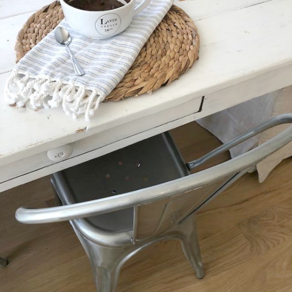 Industrial farmhouse metal chair, white painted farm table, and woven round placemat in my kitchen - Hello Lovely Studio.