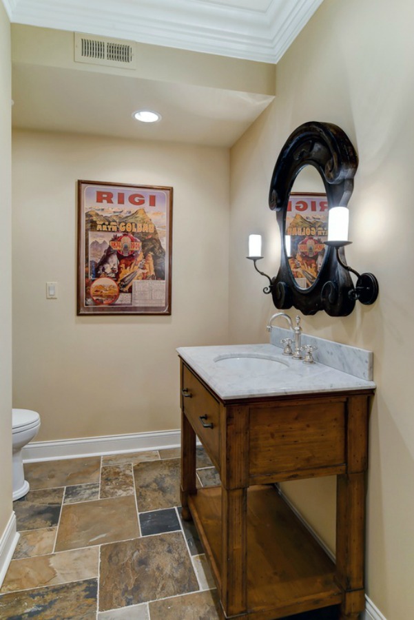French country bathroom with dark brown tiled floor and French mirror.