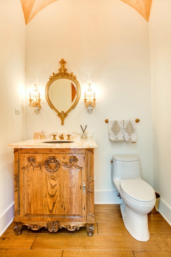 Charming powder room with French country design and a vintage style wood vanity.