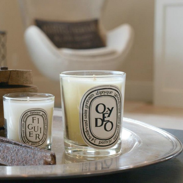 Diptyque candles upon a hotel silver oval tray in our living room - Hello Lovely Studio. Come discover more inspiring trays for layering and vignettes in Adding Tray Très Chic to Your Home.