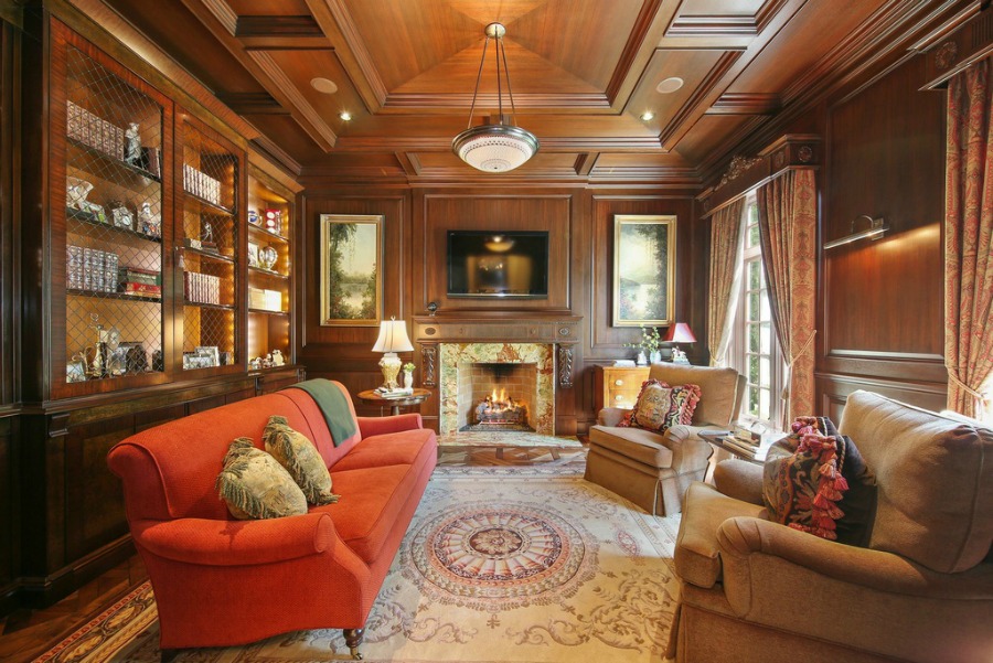 Handsome French Country den with fireplace and wood paneled walls.