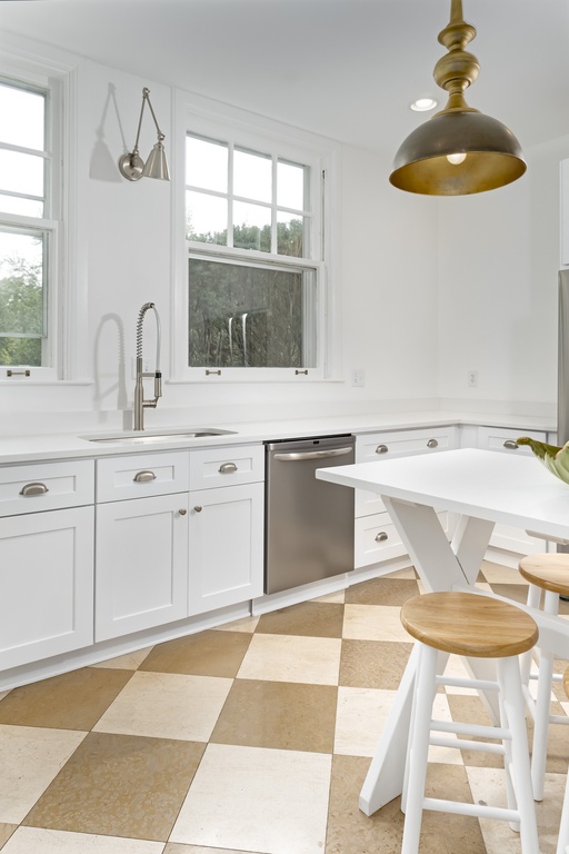 Modern French country kitchen with white Shaker cabinetry, checkerboard floor, and white orchard table with stools - Geneva, IL.