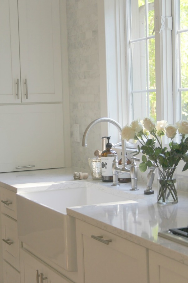 White kitchen by Hello Lovely Studio with farm sink and bridge faucet.