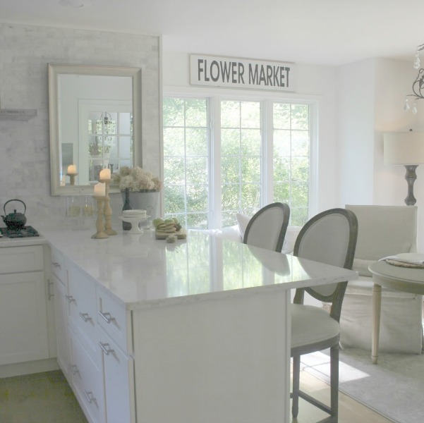 Serene white neutral kitchen with Viatera Minuet countertops, polished subway marble backsplash, and Belgian linen dining chairs. Hello Lovely Studio.