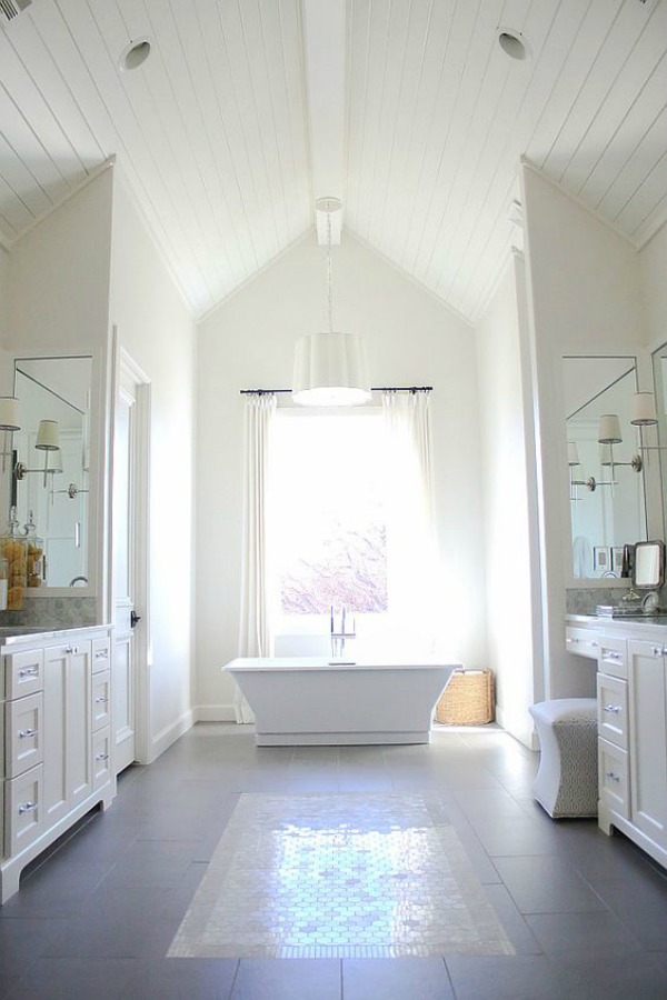 Luxurious and classic white bathroom with high ceiling, shiplap, freestanding tub, and walls painted Sherwin Williams Alabaster.