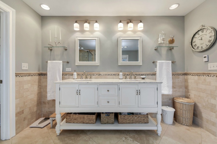 Traditional French country bathroom design with freestanding vanity and travertine tile in a grand home in Wheaton.