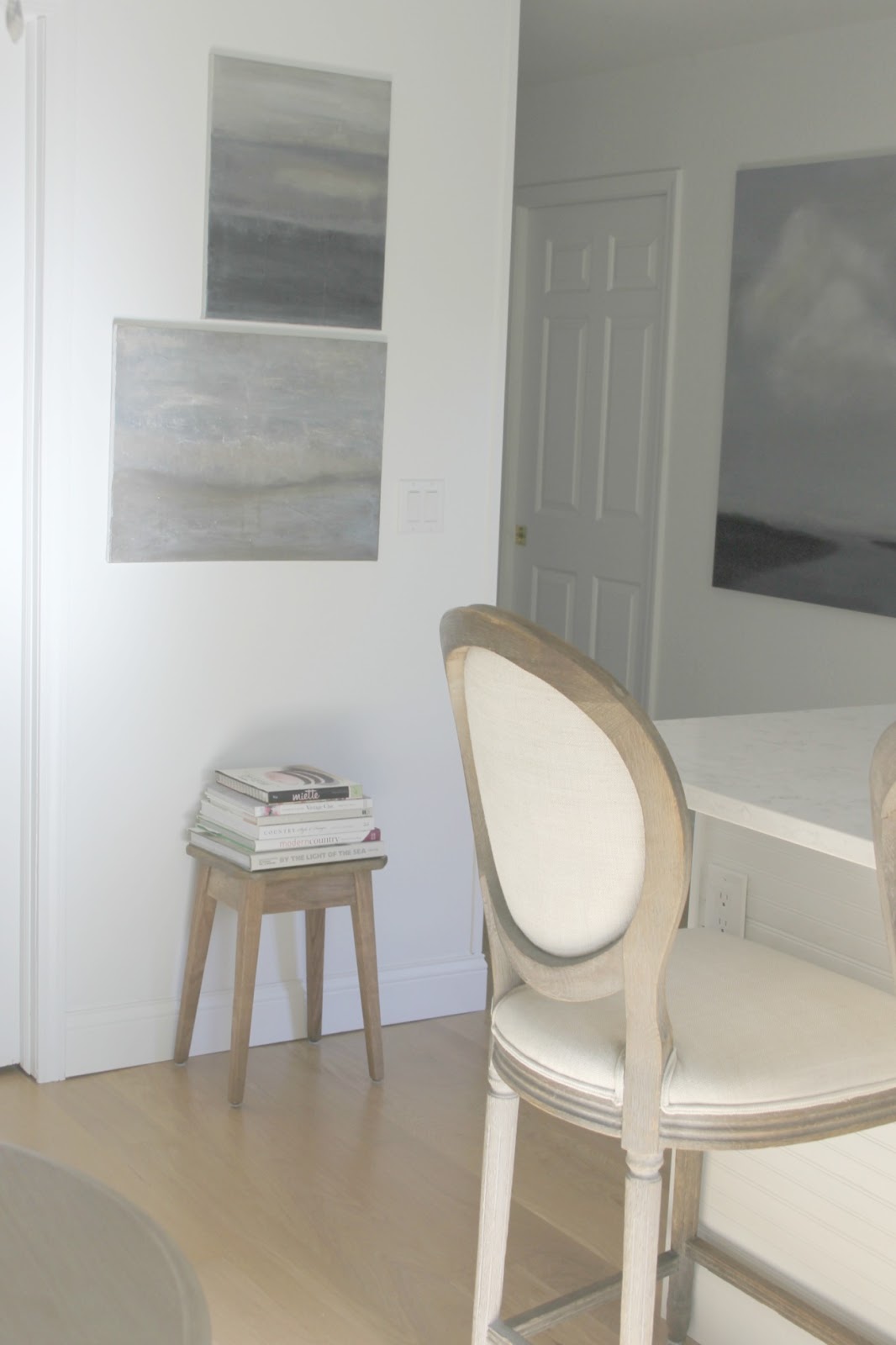 Rustic stool with books, abstract art by Michele of Hello Lovely, and Louis barstool in kitchen.