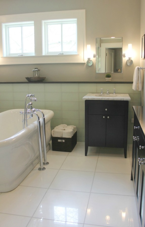 Classic luxurious bathroom design with freestanding Waterworks tub and black vanities - Hello Lovely Studio.