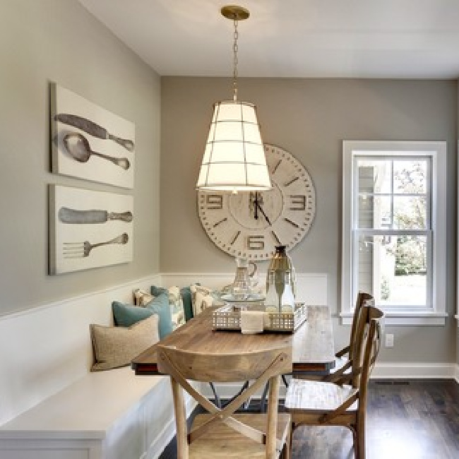 Collonade Gray paint color by Sherwin Williams on the walls of a darling breakfast nook with built-in banquette and oversized clock and art. #collonadegray #sherwinwilliams #paintcolors #lightgrey #bestneutralpaint