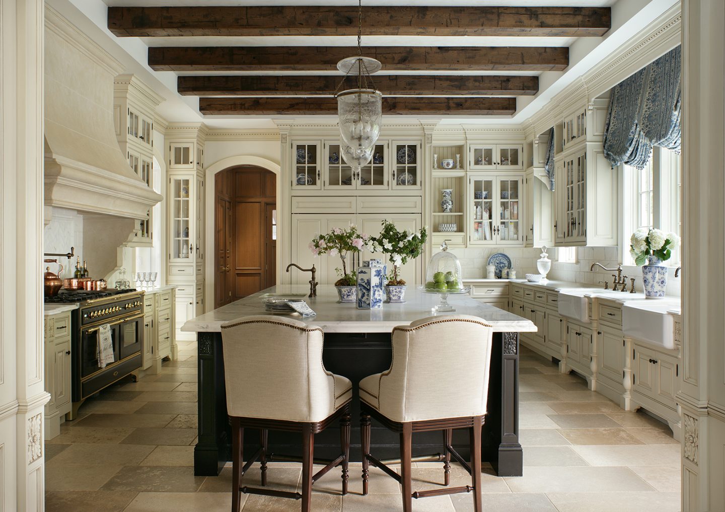 Luxurious blue and white French country kitchen with wood beams, two farm sinks, and island. The Enchanted Home.