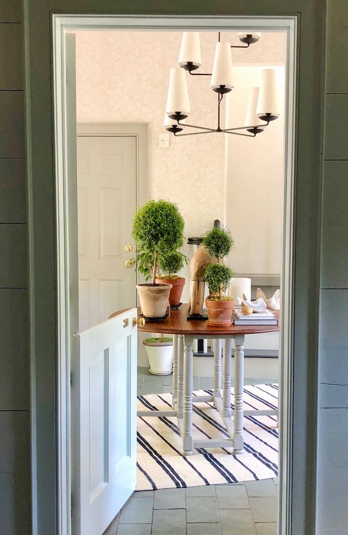 Beautiful peek inside OKL's president's Connecticut country home. Dutch door, topiaries, and an unexpected modern chandelier - photo by Quintessence.