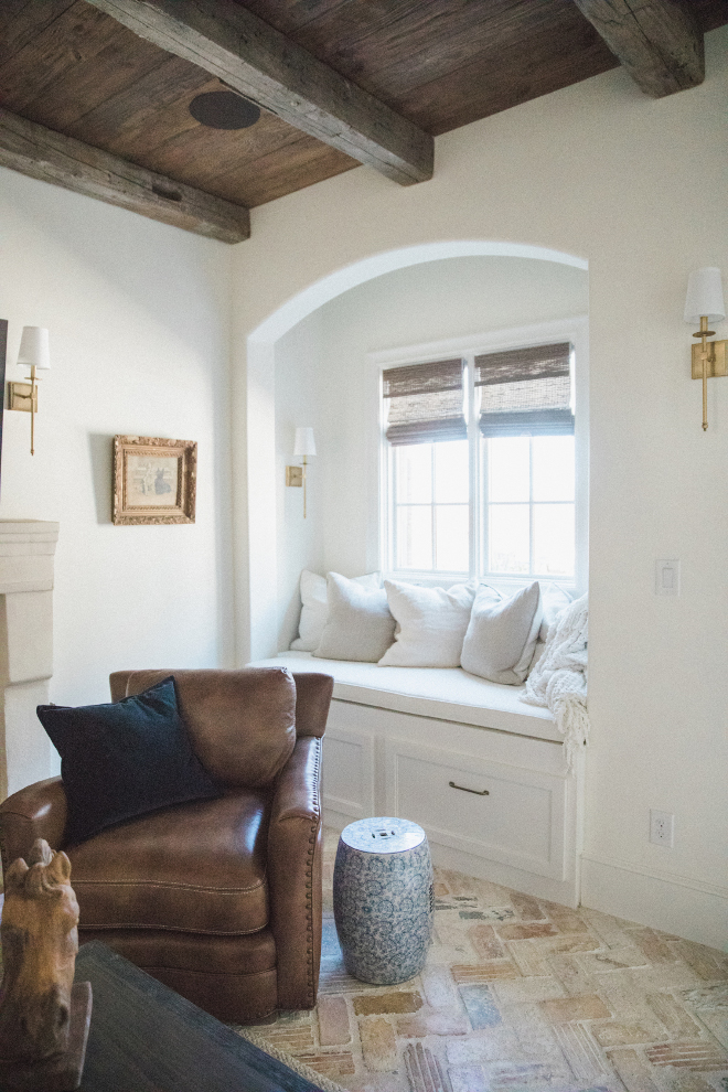 Charming French country den painted Sherwin Williams Alabaster with leather chair and arched detail over window seat nook. Brit Jones Design.