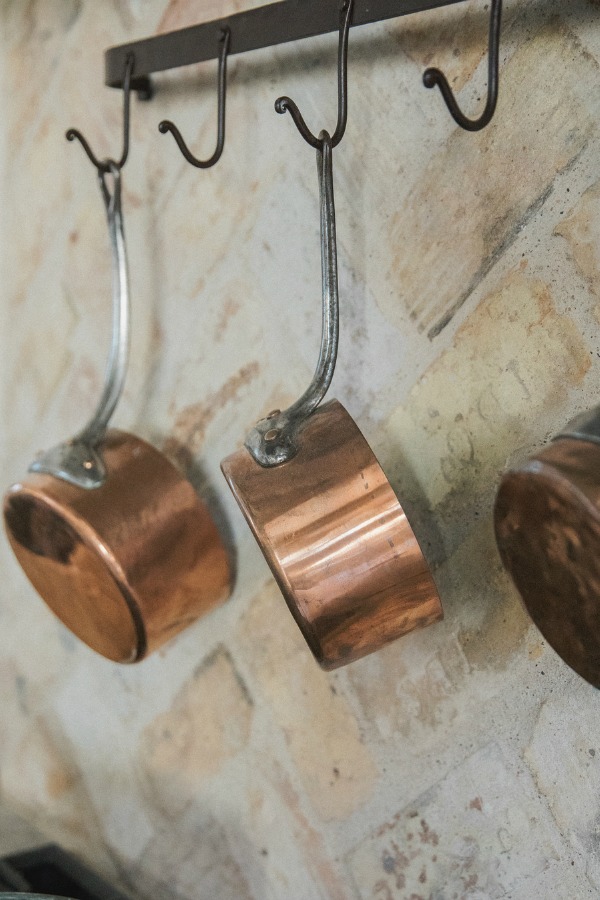 Detail of copper pots and reclaimed Chicago brick backsplash in French country kitchen by Brit Jones.