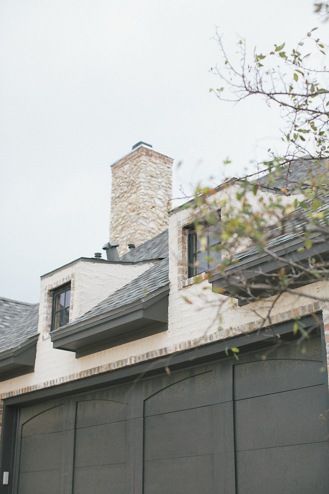 French country home exterior with arches, rustic shutters, brick, stone, and stucco. Brit Jones Design.