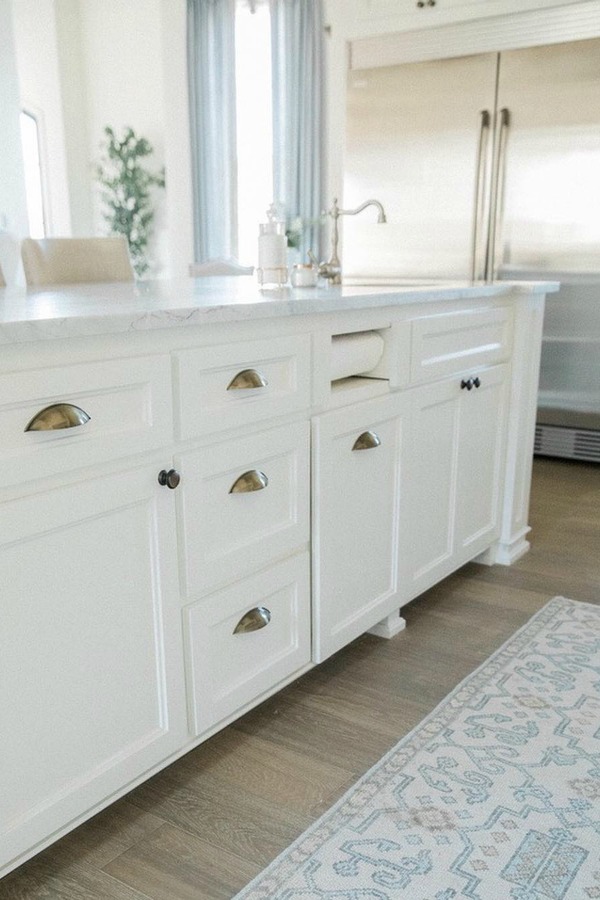 Detail of beautiful white Shaker style island topped with honed arabescato marble in French country kitchen with oak hardwood flooring. Brit Jones Design.