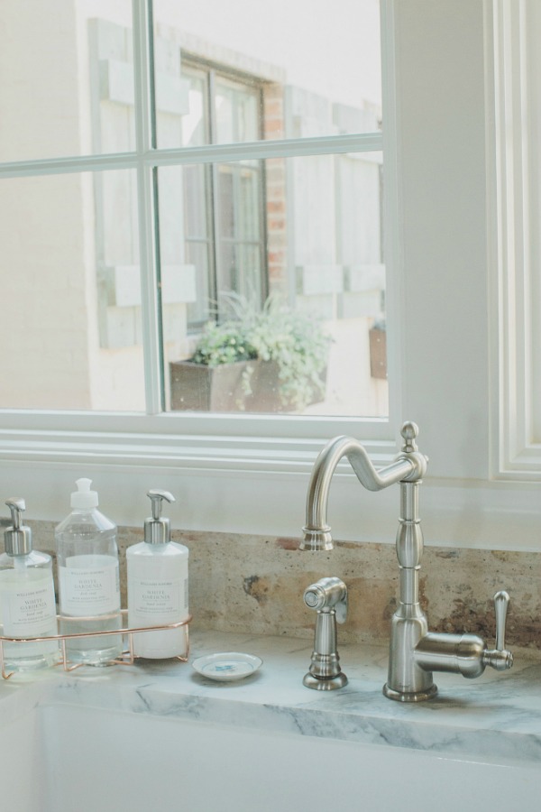 Detail of French style kitchen faucet and reclaimed Chicago brick backsplash and farm sink. Brit Jones Design.