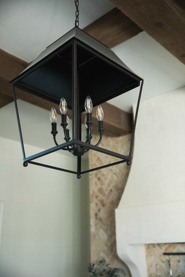 Detail of rustic French farmhouse hanging lantern pendant over island in French country kitchen by Brit Jones.