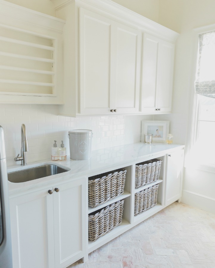 Sherwin Williams Alabaster paint color in rustic elegant French country laundry room. Open basket storage, reclaimed Chicago brick flooring, and abundant natural light. Brit Jones Design.