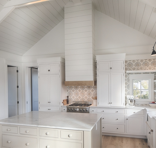 White coastal cottage kitchen with floating shelves, Shaker cabinets, white oak, and cement tile backsplash with blue accents. Lisa Furey. #coastalkitchen #whitekitchens #kitchendesign #modernfarmhouse #coastalcottage #cottagekitchen #floatingshelves #farmsink #shiplap