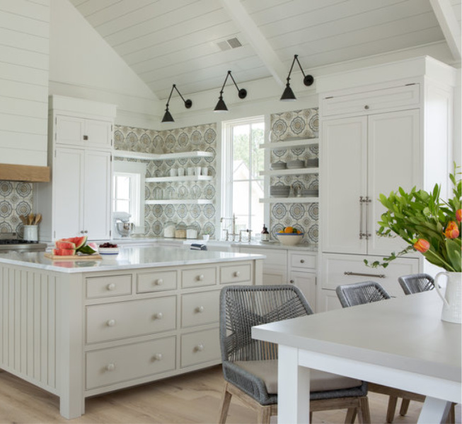 White coastal cottage kitchen with floating shelves, Shaker cabinets, white oak, and cement tile backsplash with blue accents. Lisa Furey. #coastalkitchen #whitekitchens #kitchendesign #modernfarmhouse #coastalcottage #cottagekitchen #floatingshelves #farmsink #shiplap