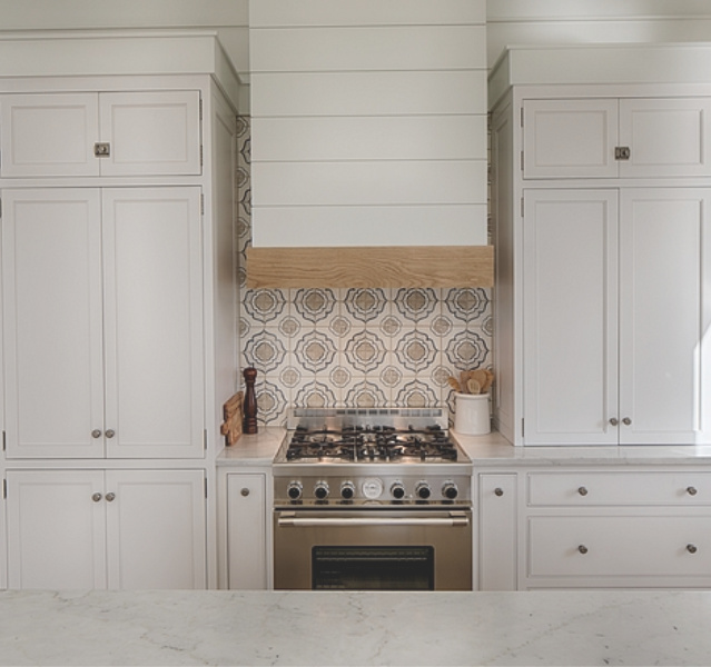 White coastal cottage kitchen with floating shelves, Shaker cabinets, white oak, and cement tile backsplash with blue accents. Lisa Furey. #coastalkitchen #whitekitchens #kitchendesign #modernfarmhouse #coastalcottage #cottagekitchen #floatingshelves #farmsink #shiplap