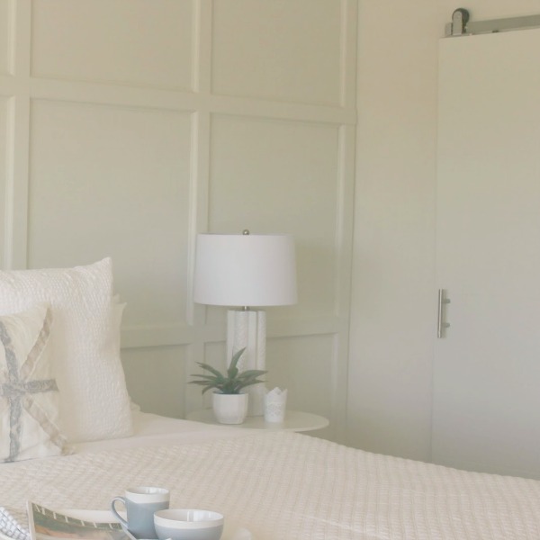 Serene and sunny white bedroom in Arizona with board and batten panel wall and sliding modern barn door. Hello Lovely Studio.