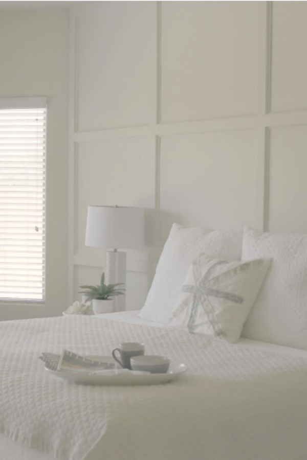 Serene and sunny white bedroom in Arizona with board and batten panel wall and sliding modern barn door. Hello Lovely Studio.