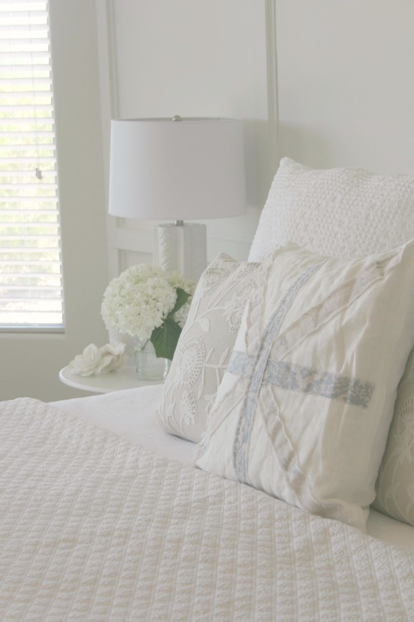 Union Jack pillow and white bedding in a serene bedroom by Hello Lovely. Come see white country interiors with a calm, airy, unfussy vibe.