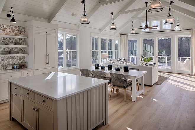 Classic white coastal cottage kitchen in Palmetto Bluff by Lisa Furey. Modern farmhouse design elements include floating shelves, shiplap, white oak flooring, and apron front farm sink.