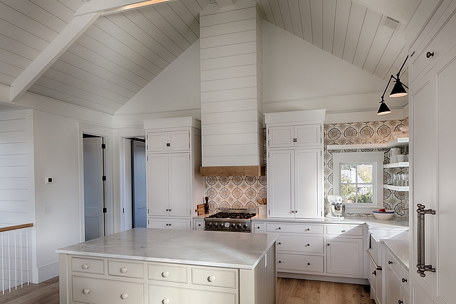 Classic white coastal cottage kitchen in Palmetto Bluff by Lisa Furey. Modern farmhouse design elements include floating shelves, shiplap, white oak flooring, and apron front farm sink.