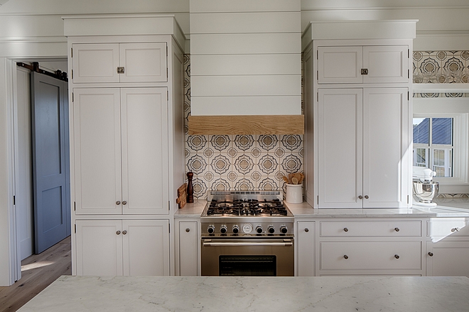 Classic white coastal cottage kitchen in Palmetto Bluff by Lisa Furey. Modern farmhouse design elements include floating shelves, shiplap, white oak flooring, and apron front farm sink.